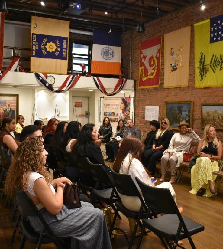 Invitados conversan bajo las banderas históricas del salón principal.